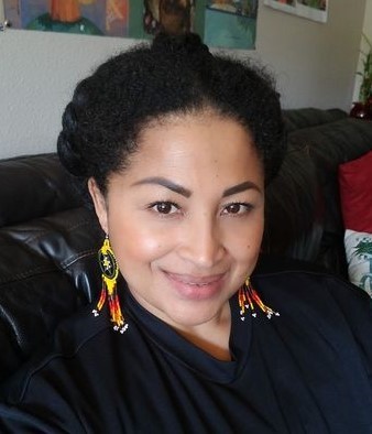 Smiling woman with braided black hair and beaded earrings