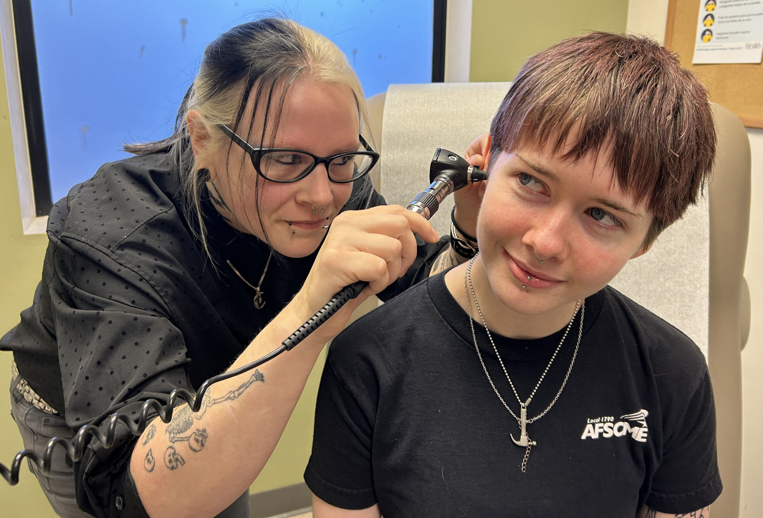 Becca, a Medical Assistant, gently uses an instrument to check the ear of a patient in the Outside In clinic.